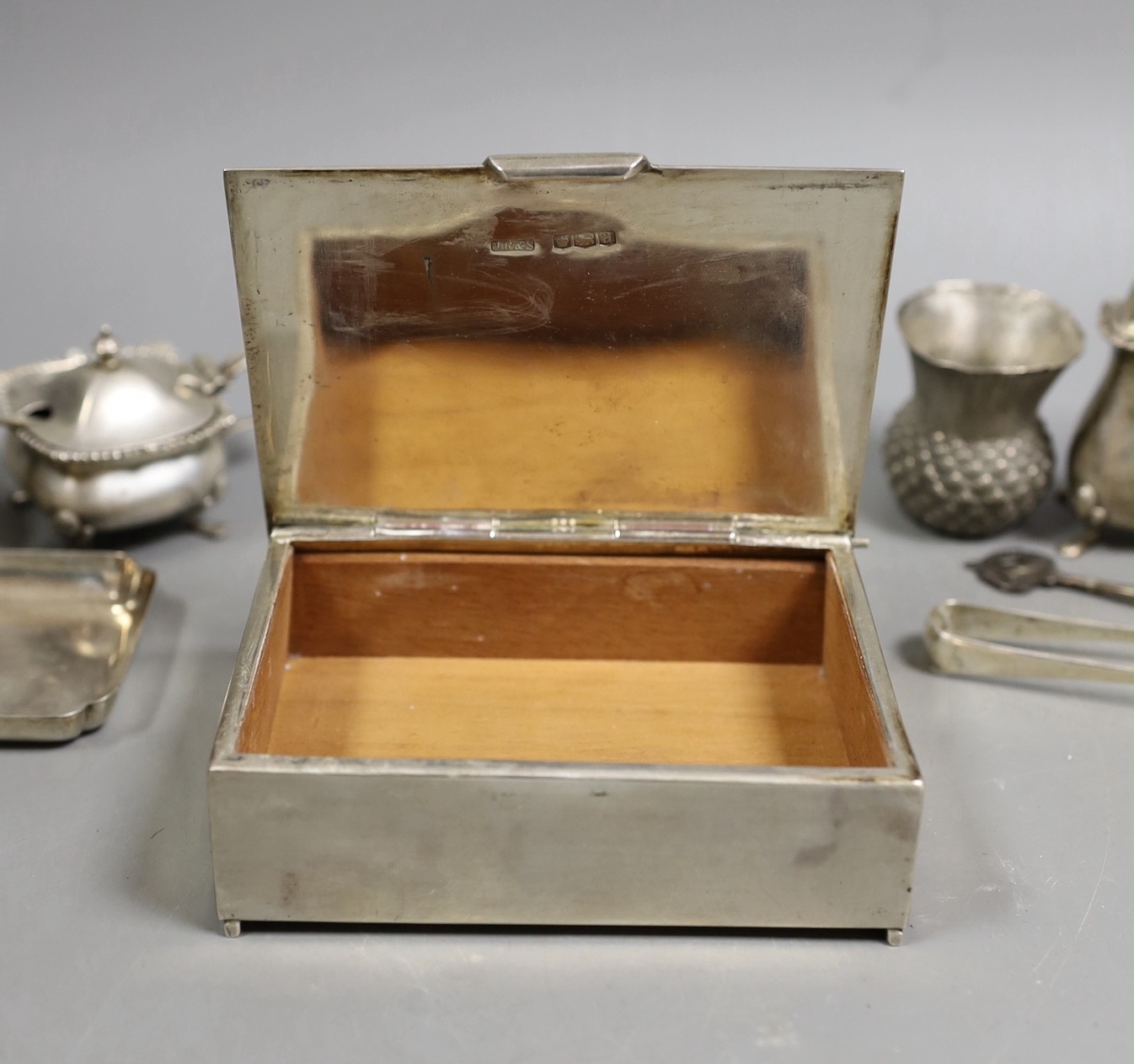 A George V silver mounted cigarette box, 11.5cm and other small sundry silver and plated items including napkin rings, condiments and small dish.